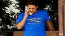 a man in a blue shirt talking on a phone