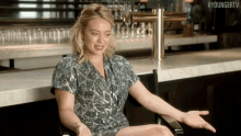 a woman is sitting in a chair in front of a bar with her hands outstretched .