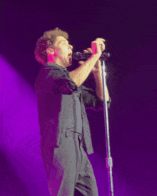 a young man singing into a microphone on stage