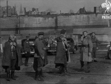 a black and white photo of a group of soldiers standing in front of a building .