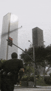 a man in a black shirt is walking down a street in front of a tall building