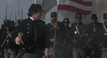a man in a military uniform is holding an american flag in his hand .