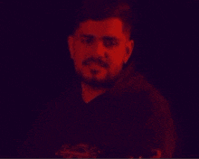 a man with a beard wearing a black hoodie is smiling with his arms crossed .