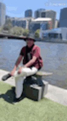 a man is sitting on a bench next to a river .