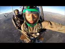 a man in a green helmet is taking a selfie with another man