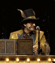 a man in a top hat is speaking into a microphone while wearing a gold jacket