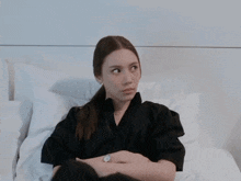a woman in a black shirt is sitting on a bed