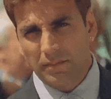 a close up of a man in a suit and tie with earrings on his ear .