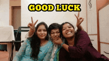 three women are posing for a picture with the words good luck behind them