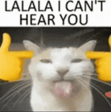 a cat is sticking its tongue out in front of a sign that says `` lalala i can t hear you '' .