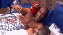 a man and a woman are laying in bed with a stuffed parrot on their chest .