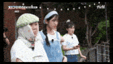 three girls are standing next to each other in front of a tv screen