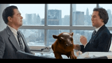 two men are sitting at a table with a pig sitting on it