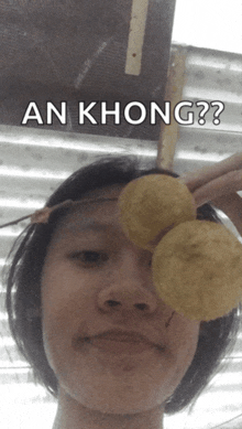 a woman is holding two potato chips in front of her eye and says an khong on the bottom