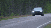 a black jeep is driving down a country road