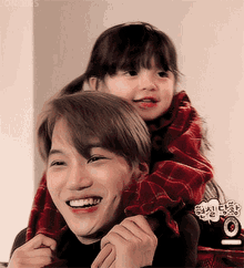 a man is carrying a little girl on his shoulders and smiling for the camera