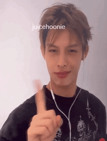 a young man wearing ear buds and a black shirt with the name juicehoonie on the top