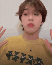 a young man wearing a yellow shirt with black bears on it is making a funny face