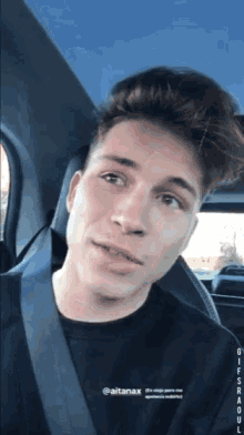 a young man is sitting in a car with a black shirt on