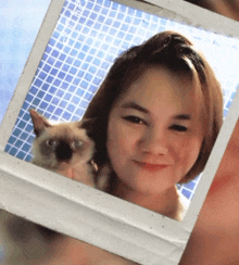 a polaroid picture of a woman holding a cat with a blue background