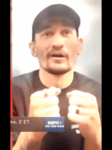 a man wearing a black shirt and a black hat is talking in front of a sign that says pay per view