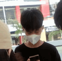 a man wearing a mask is looking at his cell phone