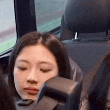 a woman is sitting in a car with her eyes closed .