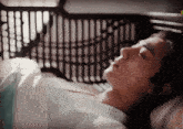 a man is laying in a bed with his eyes closed and a pillow with a greek key pattern on it
