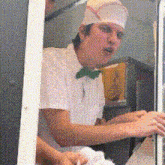 a man wearing a white hat and a green bow tie is standing in front of a window