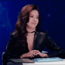 a woman in a black leather jacket sitting at a desk