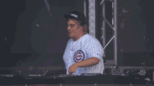 a man wearing a chicago cubs jersey is playing a dj set