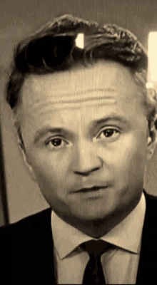 a man in a suit and tie is making a serious face