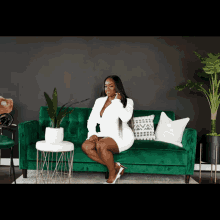 a woman is sitting on a green couch in a white dress