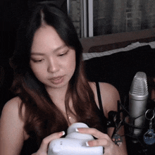 a woman sitting in front of a microphone holding a white object