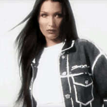 a woman with long hair is wearing a black and white denim jacket and a white shirt .