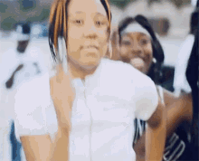 a woman in a white shirt is talking on a cell phone in front of a group of people .