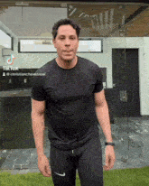 a man in a black shirt is standing in front of a glass wall with a tiktok sticker on his shirt