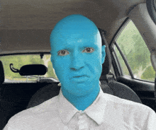 a man with blue paint on his face is sitting in the driver 's seat of a car