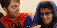 a man in a spiderman costume is talking to another man in glasses