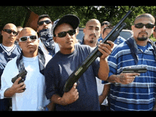 a man holding a shotgun stands in front of a group of men