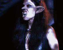 a close up of a woman 's face with long black hair and fangs