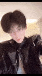 a blurry picture of a young man in a leather jacket and tie .