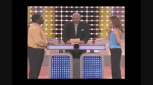 a man and a woman are standing in front of a game show host holding a card that says ' celebrity ' on it
