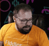 a man with a beard and glasses wears a yellow fiddler shirt