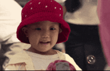 a little girl wearing a red knitted hat looks at the camera