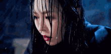 a close up of a woman 's face with wet hair in the rain .