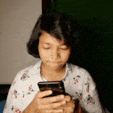 a woman in a floral shirt is looking at her cell phone