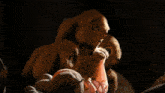 two stuffed animals are sitting next to each other in a dark room and one is holding something in its mouth