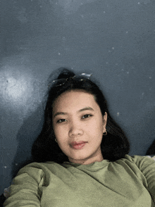 a woman wearing sunglasses and a green shirt is laying on a bed