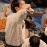 a man in a white shirt is drinking from a glass with a treasure sign in the background